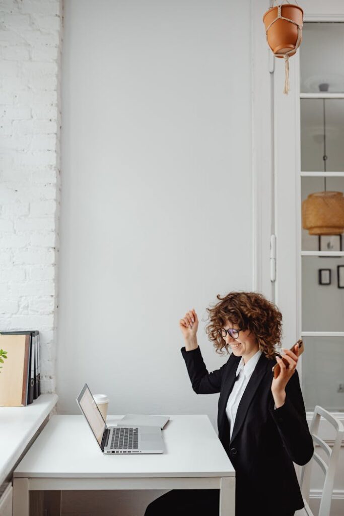 A Woman in Black Blazer Sitting in Front of the Table with Laptop